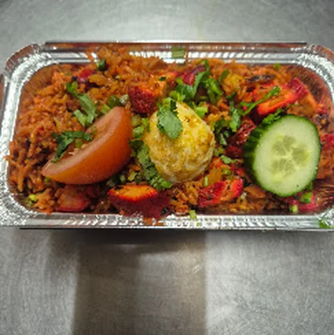 Biryani in a foil tray with salad